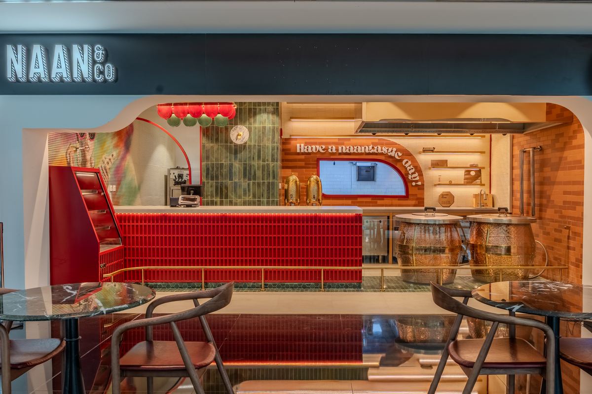 The Naan & Co storefront, with its illuminated sign, red tiled counter and a wall reading Have a naantastic day
